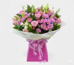 A lush premium flower bouquet featuring pink roses, purple chrysanthemums, and lilies in a pink gift box with a checkered ribbon.