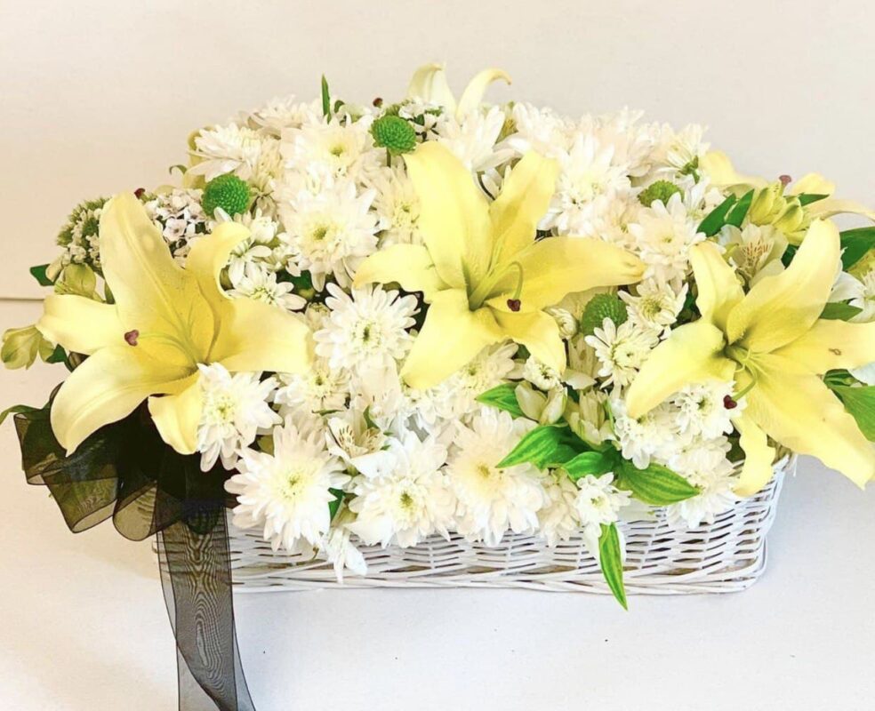 Basket of white and yellow flowers arranged beautifully.