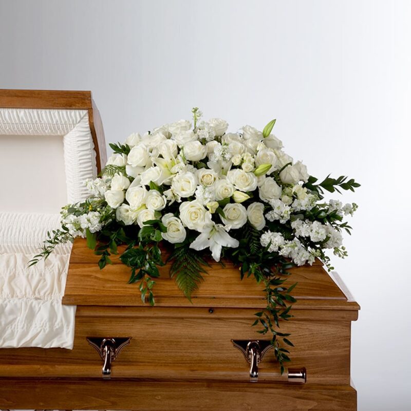 A wooden coffin adorned with a white flower arrangement.