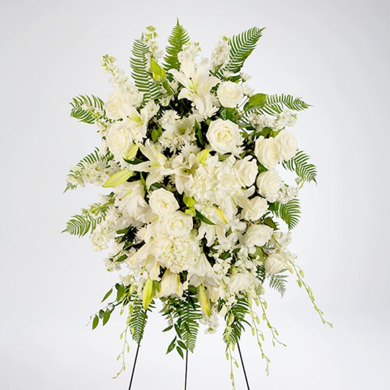 Elegant white floral arrangement on a stand with assorted blooms.