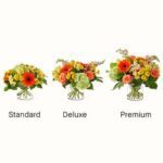 A comparison of three floral arrangements—Standard, Deluxe, and Premium—featuring bright orange gerbera daisies, yellow roses, and green hydrangeas in clear glass vases.