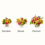 Comparison of three sizes of the "Best Day" flower bouquet: Standard, Deluxe, and Premium, featuring sunflowers, roses, lilies, and snapdragons in glass vases.