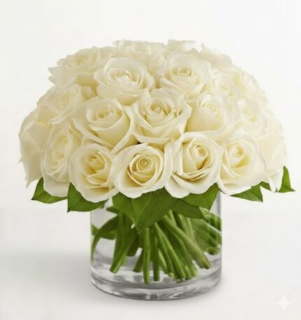 A dense, dome-shaped arrangement of premium white roses in a clear glass cylinder vase with visible green stems and leaves.