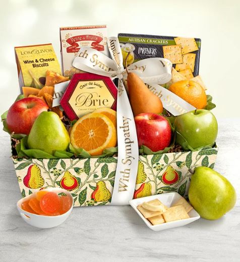 A "With Deepest Sympathy" gourmet fruit and snack gift basket featuring fresh apples, pears, oranges, Brie cheese, artisan crackers, and wine biscuits, decorated with a white sympathy ribbon.