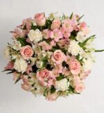 Alt text: A lush bouquet of soft pink roses, white carnations, and pink and white alstroemeria flowers arranged together against a white background