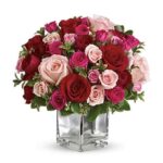Romantic bouquet of red, pink, and blush roses with green filler arranged in a clear square glass vase