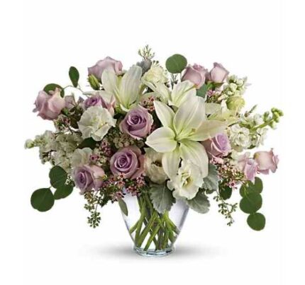 Elegant bouquet of white lilies, lavender roses, white hydrangeas, and eucalyptus in a clear glass vase