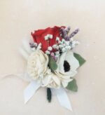Red preserved rose boutonniere with ivory sola wood flowers, baby's breath, and lavender accents, tied with a white satin ribbon