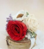 Preserved red rose corsage with an ivory sola wood rose, white accent flower, and lavender sprigs on a natural birch wood slice, tied with white ribbon