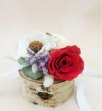 Preserved red rose and white sola flower corsage on a natural birch wood slice, accented with purple filler flowers, eucalyptus leaves, and white ribbon.