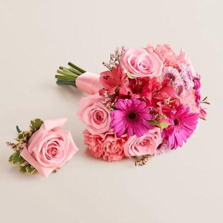 Matching pink prom bouquet and boutonniere set on a light background. The bouquet features pink roses, hot pink gerbera daisies, pink carnations, and alstroemeria wrapped with a pale pink ribbon. The boutonniere is a single pink rose with small accent flowers and greenery.