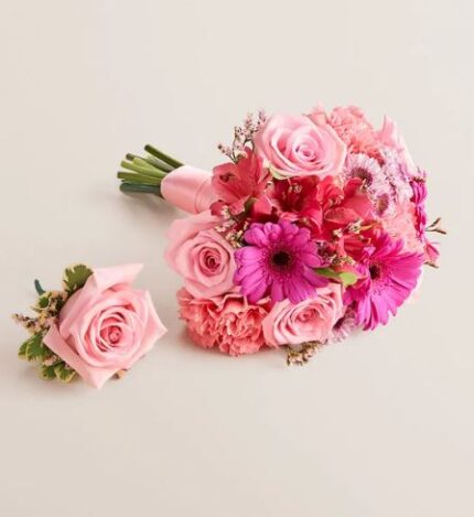Matching pink prom bouquet and boutonniere set on a light background. The bouquet features pink roses, hot pink gerbera daisies, pink carnations, and alstroemeria wrapped with a pale pink ribbon. The boutonniere is a single pink rose with small accent flowers and greenery.