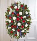 A grand and elegant floral tribute in patriotic tones, designed to honor a loved one with dignity and grace during a memorial or funeral service.