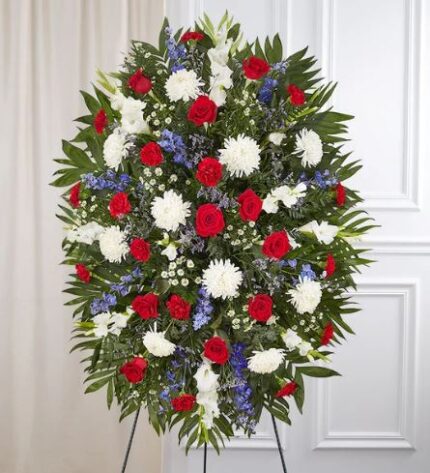 A grand and elegant floral tribute in patriotic tones, designed to honor a loved one with dignity and grace during a memorial or funeral service.