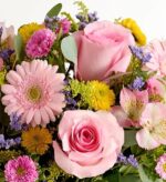 Close-up of a vibrant spring flower bouquet featuring pink roses, pink gerbera daisies, light pink alstroemeria, yellow and magenta chrysanthemums, small purple statice, and fresh eucalyptus leaves.
