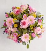 Top-down view of a round spring bouquet with pink roses, pink gerbera daisies, light pink alstroemeria, yellow button chrysanthemums, small purple filler flowers, and fresh eucalyptus leaves, arranged on a light gray background.